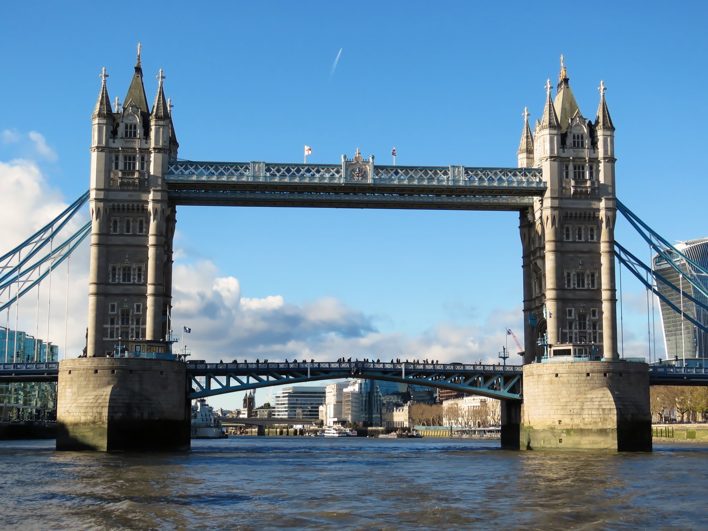 Full exterior view of Tower Bridge seen from the Pool of London along the River Thames.