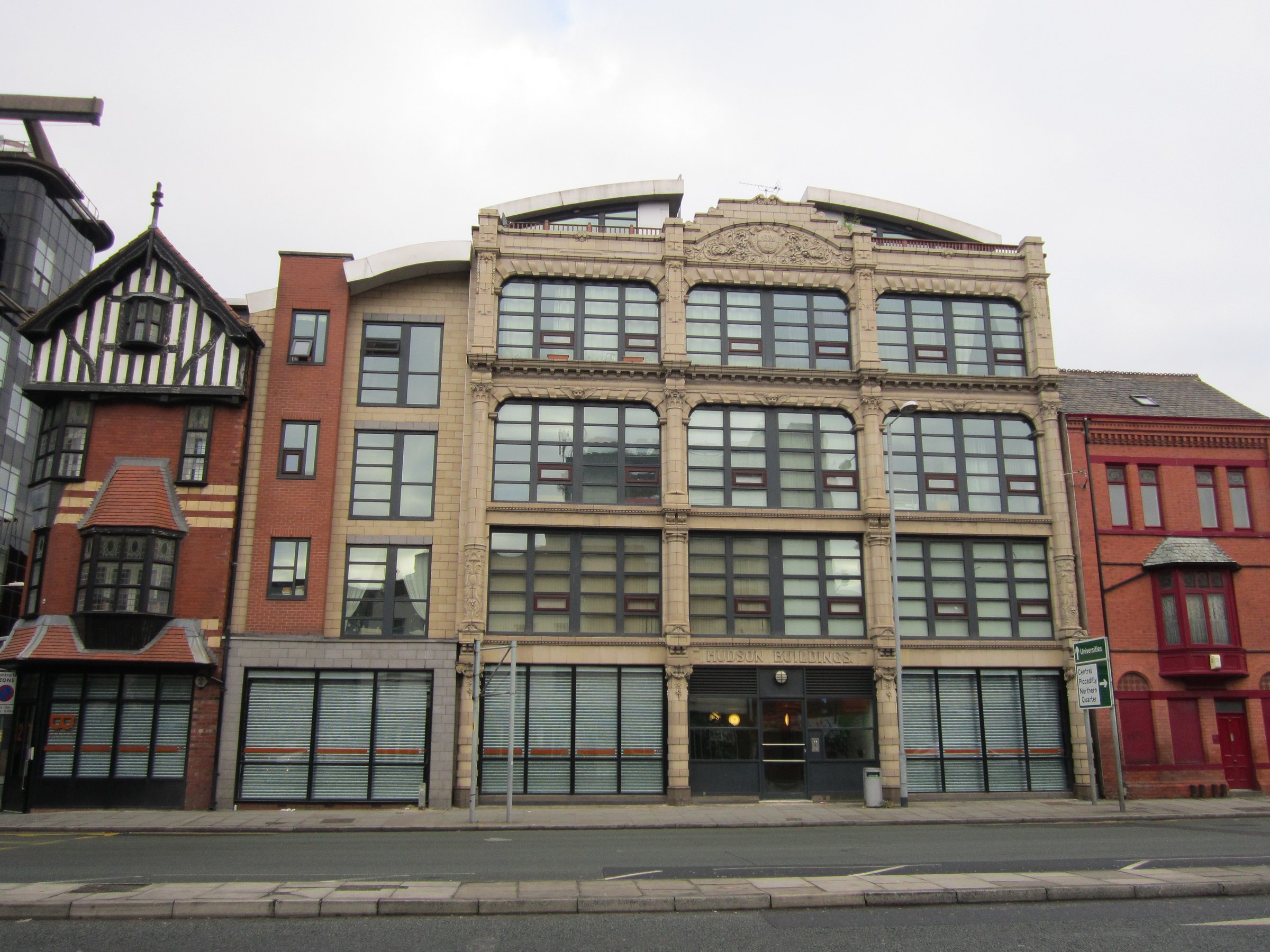 Warm-toned historic Victorian-era brick building on a quiet Manchester street.